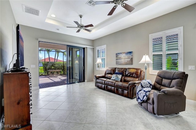 living area with light tile patterned flooring, a raised ceiling, visible vents, and baseboards