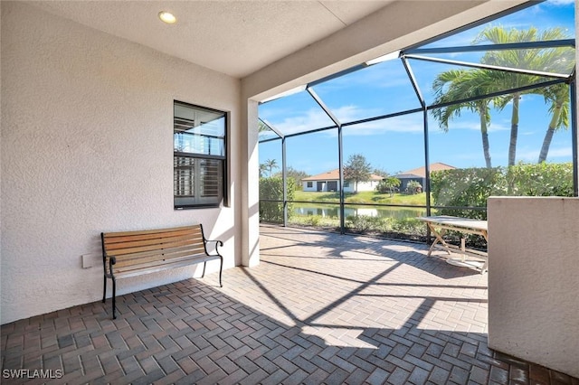 view of patio featuring a lanai and a water view