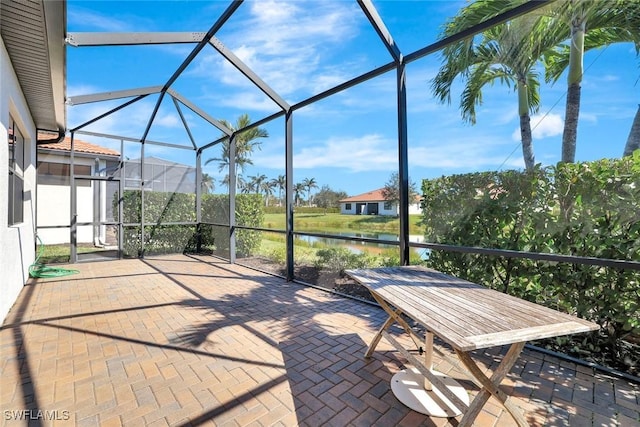 view of patio / terrace featuring a water view and glass enclosure