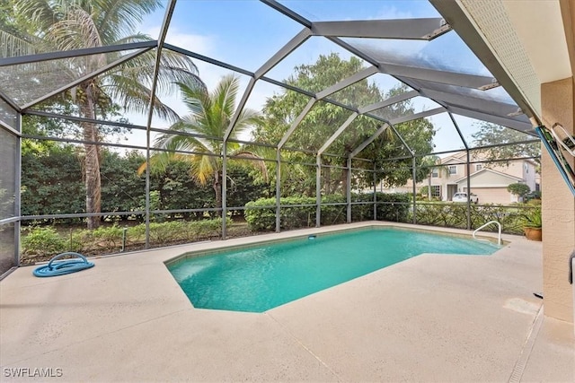 outdoor pool featuring glass enclosure and a patio