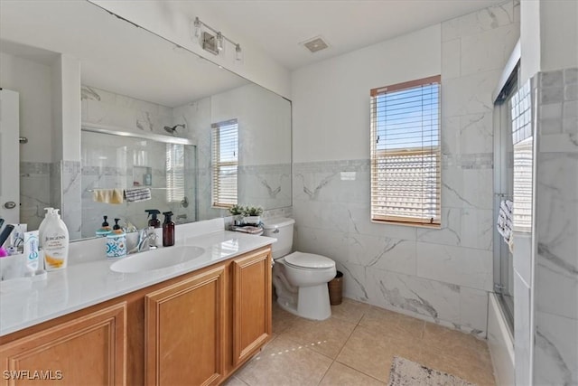 full bathroom with tile walls, visible vents, toilet, a shower with shower door, and vanity