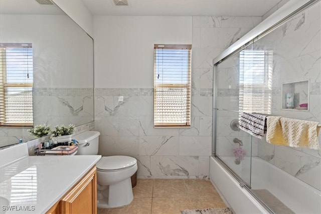 full bath with enclosed tub / shower combo, toilet, tile walls, vanity, and tile patterned floors