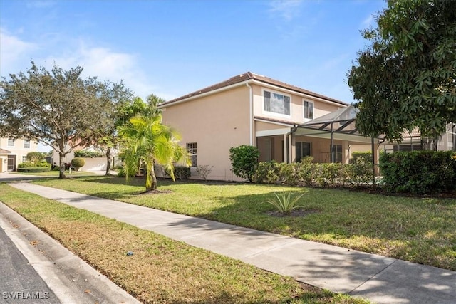 view of front of house with a lanai, stucco siding, and a front yard