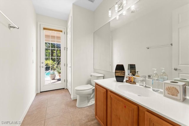 bathroom with toilet, vanity, baseboards, and tile patterned floors