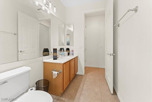 bathroom with toilet, vanity, baseboards, and tile patterned floors