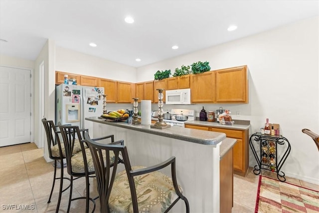 kitchen featuring light tile patterned floors, recessed lighting, white appliances, a breakfast bar, and a center island