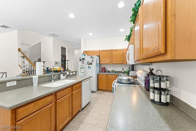 kitchen featuring brown cabinets, recessed lighting, visible vents, a sink, and white appliances