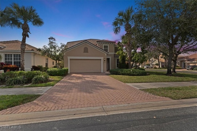 view of front of home with an attached garage, a front lawn, decorative driveway, and stucco siding