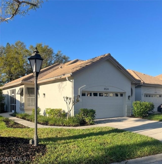 view of front of house with driveway, a front yard, an attached garage, and stucco siding