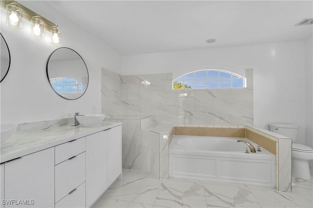 full bath featuring marble finish floor, a garden tub, visible vents, toilet, and a sink