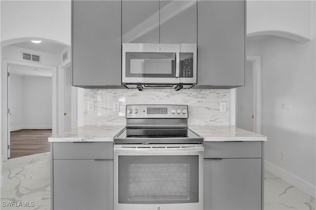 kitchen with arched walkways, marble finish floor, stainless steel appliances, gray cabinets, and visible vents