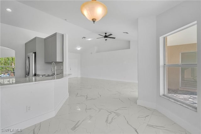 interior space featuring arched walkways, marble finish floor, a sink, and baseboards