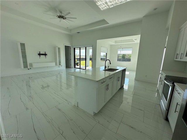 kitchen with a tray ceiling, marble finish floor, stainless steel electric range oven, and a sink