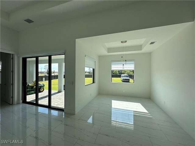 spare room with marble finish floor, baseboards, visible vents, and a raised ceiling