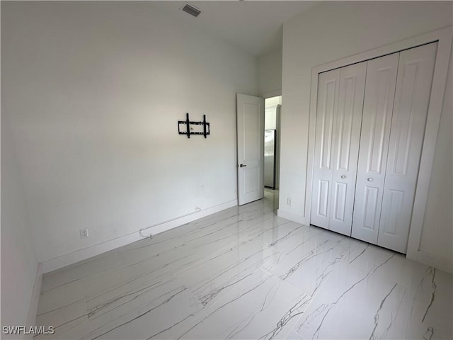 unfurnished bedroom with a closet, marble finish floor, visible vents, and baseboards