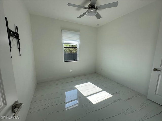 spare room with a ceiling fan and marble finish floor