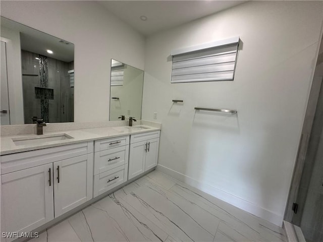 bathroom with double vanity, a stall shower, a sink, and baseboards