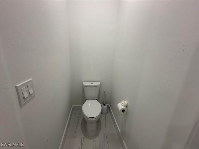 bathroom with toilet and baseboards