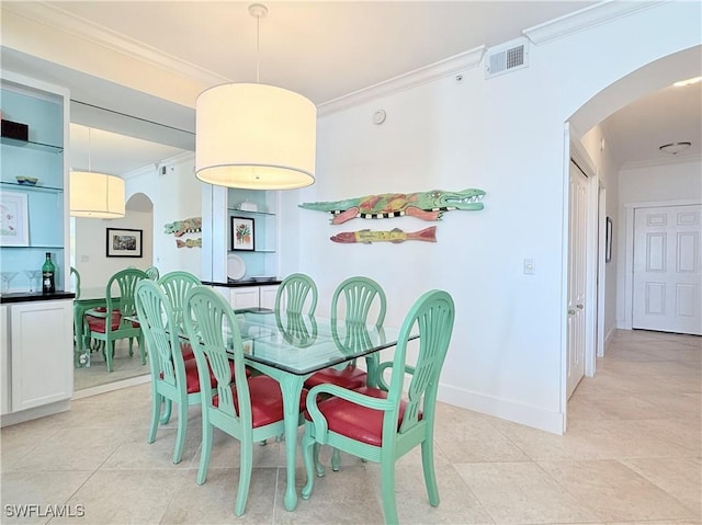 dining space with baseboards, visible vents, arched walkways, ornamental molding, and light tile patterned flooring