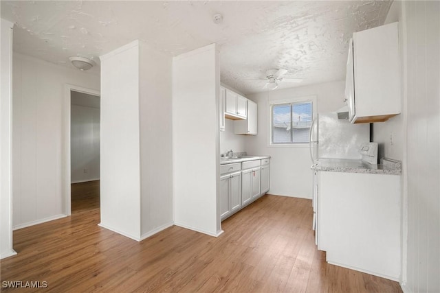 kitchen with ceiling fan, a textured ceiling, light wood-style flooring, and white cabinetry