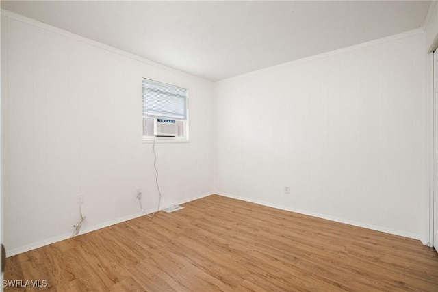 spare room featuring ornamental molding, light wood-type flooring, cooling unit, and baseboards