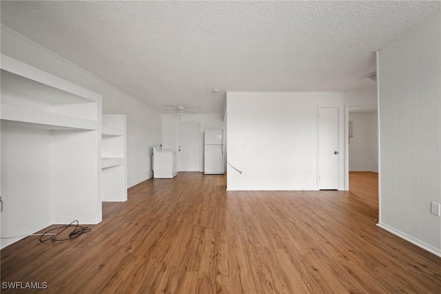 unfurnished room featuring washer / dryer, a ceiling fan, a textured ceiling, and wood finished floors