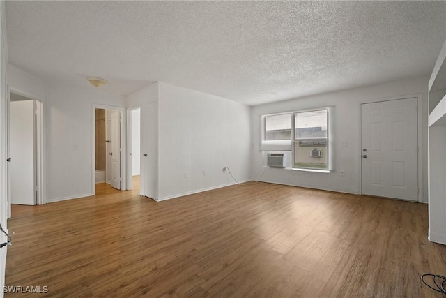 unfurnished living room featuring a textured ceiling, baseboards, and wood finished floors