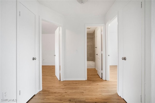 corridor featuring light wood-type flooring and baseboards