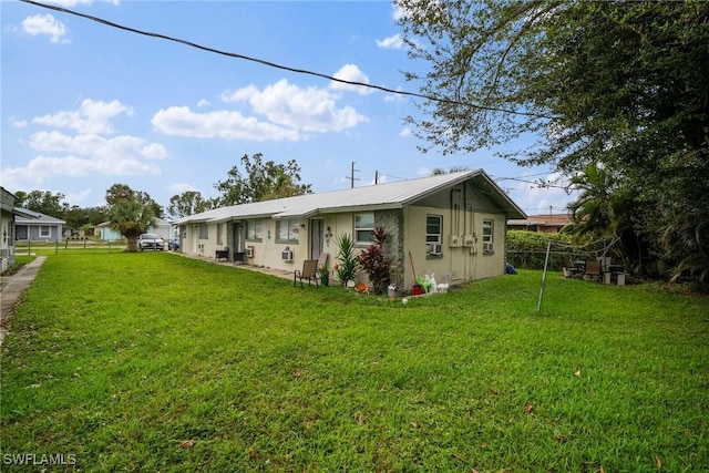 rear view of house featuring stucco siding, a lawn, and fence