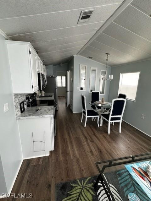 kitchen with visible vents, dark wood-type flooring, and stainless steel microwave