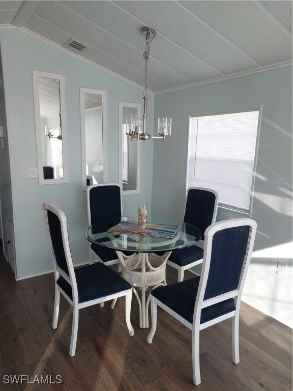 dining space with crown molding, visible vents, vaulted ceiling, and wood finished floors