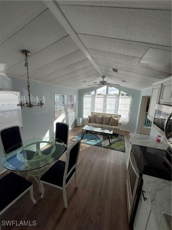 dining area featuring ceiling fan with notable chandelier, lofted ceiling, visible vents, and wood finished floors