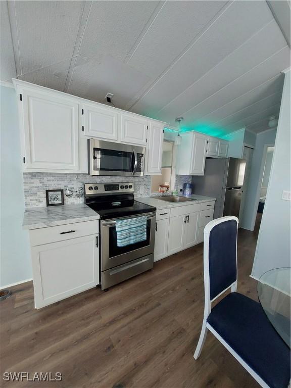 kitchen featuring appliances with stainless steel finishes, dark wood-style flooring, white cabinets, and backsplash