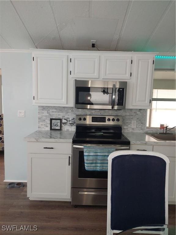 kitchen featuring stainless steel appliances, dark wood-style flooring, a sink, and light countertops