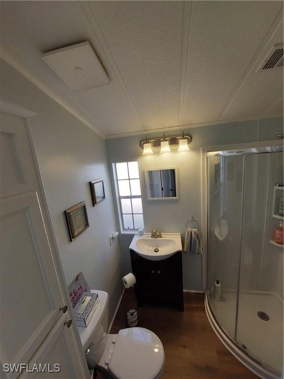 full bath featuring a stall shower, vanity, toilet, and wood finished floors