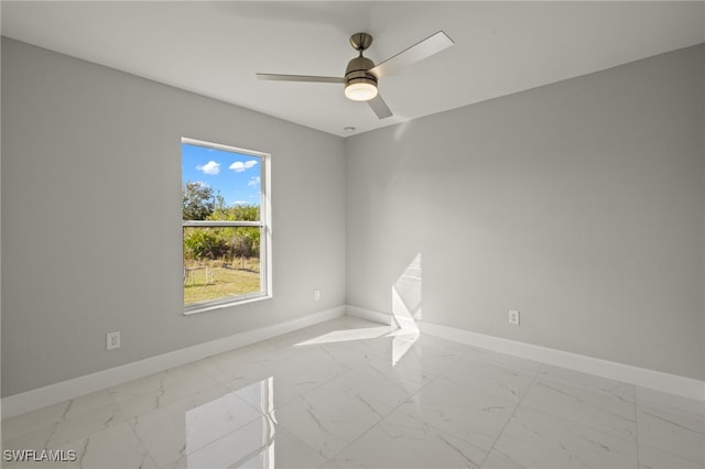 spare room with marble finish floor, a ceiling fan, and baseboards