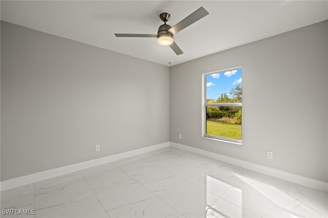 spare room featuring marble finish floor, ceiling fan, and baseboards