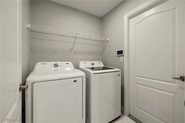 clothes washing area featuring laundry area, marble finish floor, and washer and clothes dryer