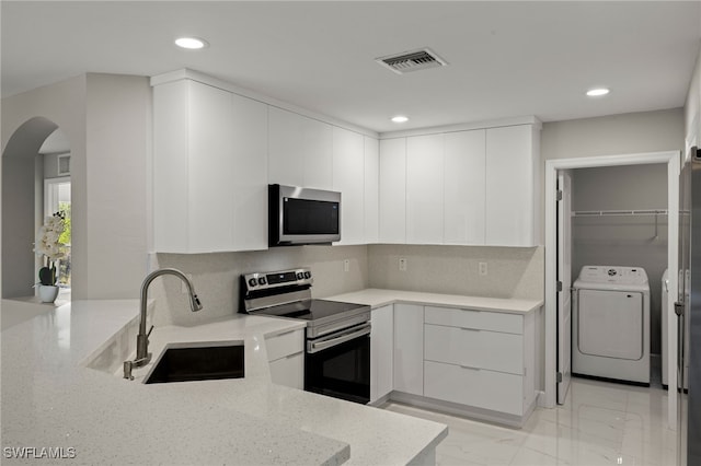 kitchen featuring washing machine and clothes dryer, visible vents, appliances with stainless steel finishes, a sink, and modern cabinets