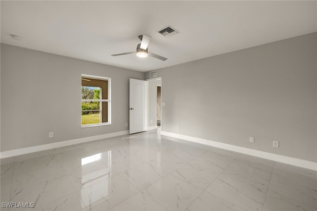 spare room with marble finish floor, visible vents, ceiling fan, and baseboards