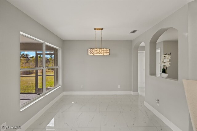 unfurnished room featuring marble finish floor, baseboards, visible vents, and arched walkways