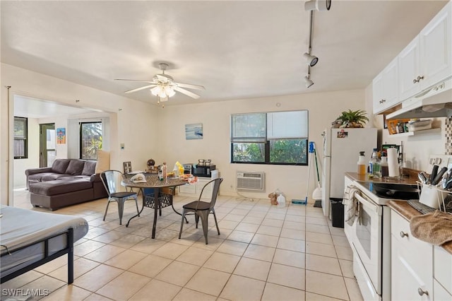 dining room with a wall unit AC, rail lighting, light tile patterned flooring, and a ceiling fan