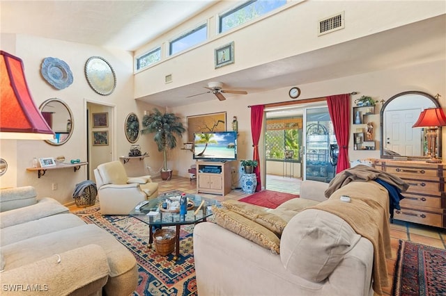 tiled living area with a towering ceiling, ceiling fan, visible vents, and a wealth of natural light