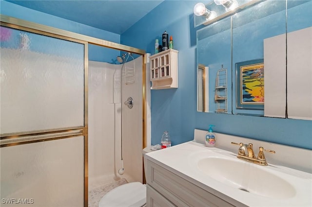 bathroom featuring toilet, a shower stall, and vanity