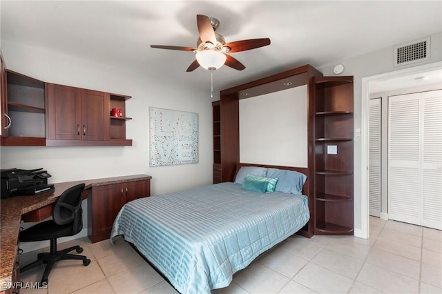 bedroom with built in desk, light tile patterned floors, a closet, visible vents, and a ceiling fan