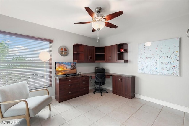 office area featuring built in study area, ceiling fan, baseboards, and light tile patterned floors