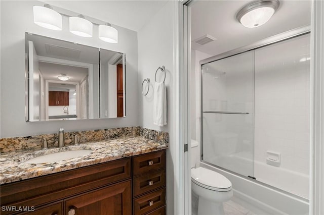 full bath with visible vents, combined bath / shower with glass door, vanity, and toilet