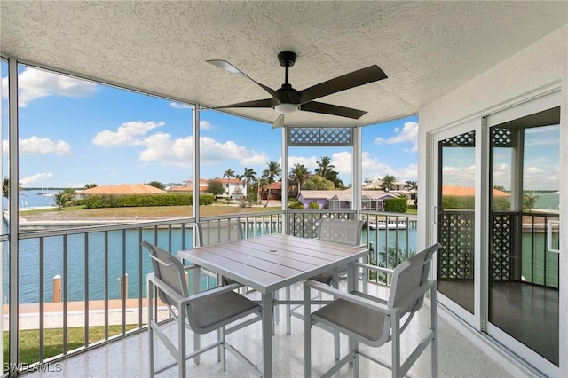 balcony featuring a water view, a sunroom, and a ceiling fan