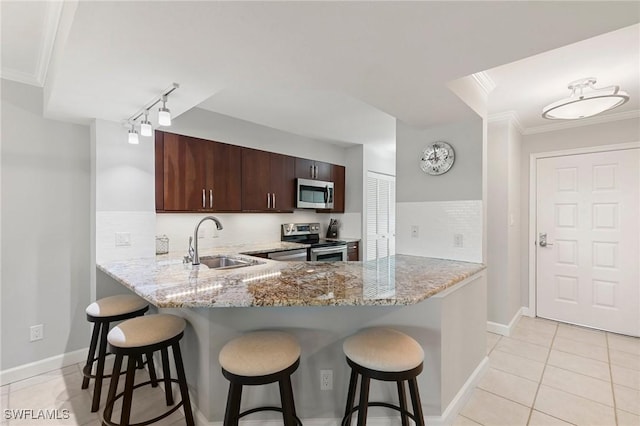 kitchen featuring ornamental molding, appliances with stainless steel finishes, a breakfast bar area, and a sink