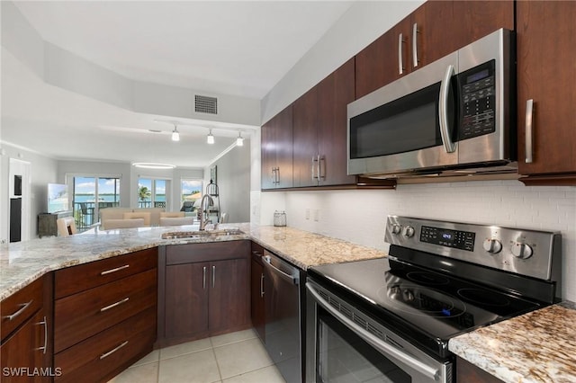 kitchen with appliances with stainless steel finishes, a sink, visible vents, and decorative backsplash